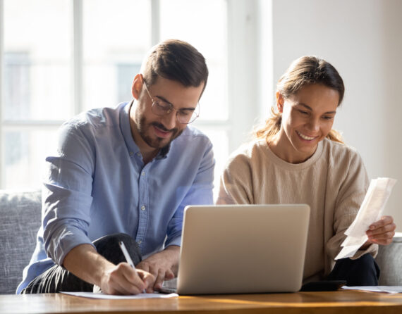 Happy,Couple,Using,Laptop,,Calculating,Domestic,Bills,,Mortgage,Or,Loan